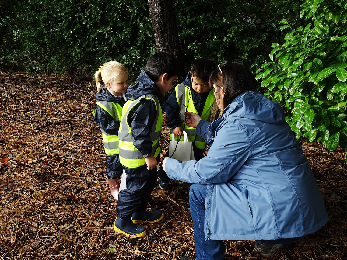 Nursery pupils pick up leaves and twigs during an autumn walk