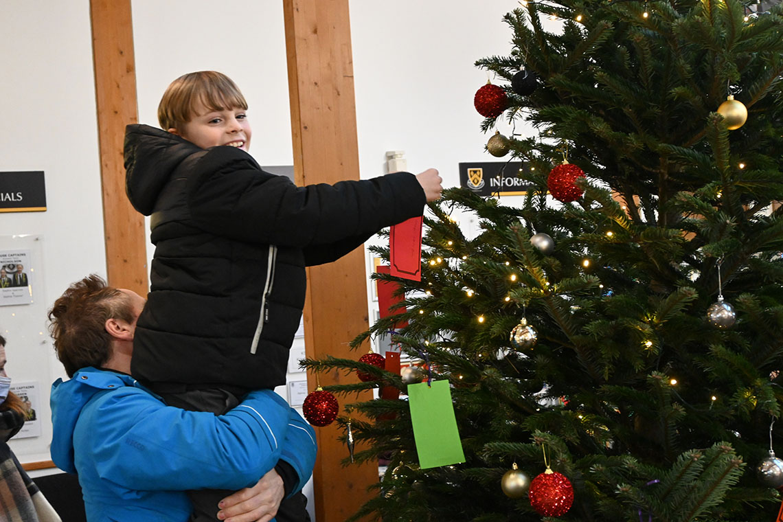 Christmas Wishes 2021 - boy hanging wish with parent