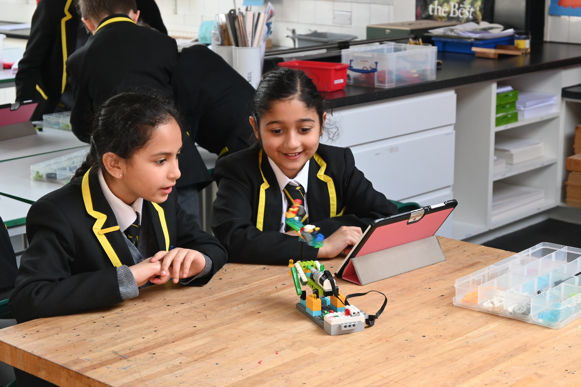 Junior School girls smiling at model during a LEGO Robotics workshop